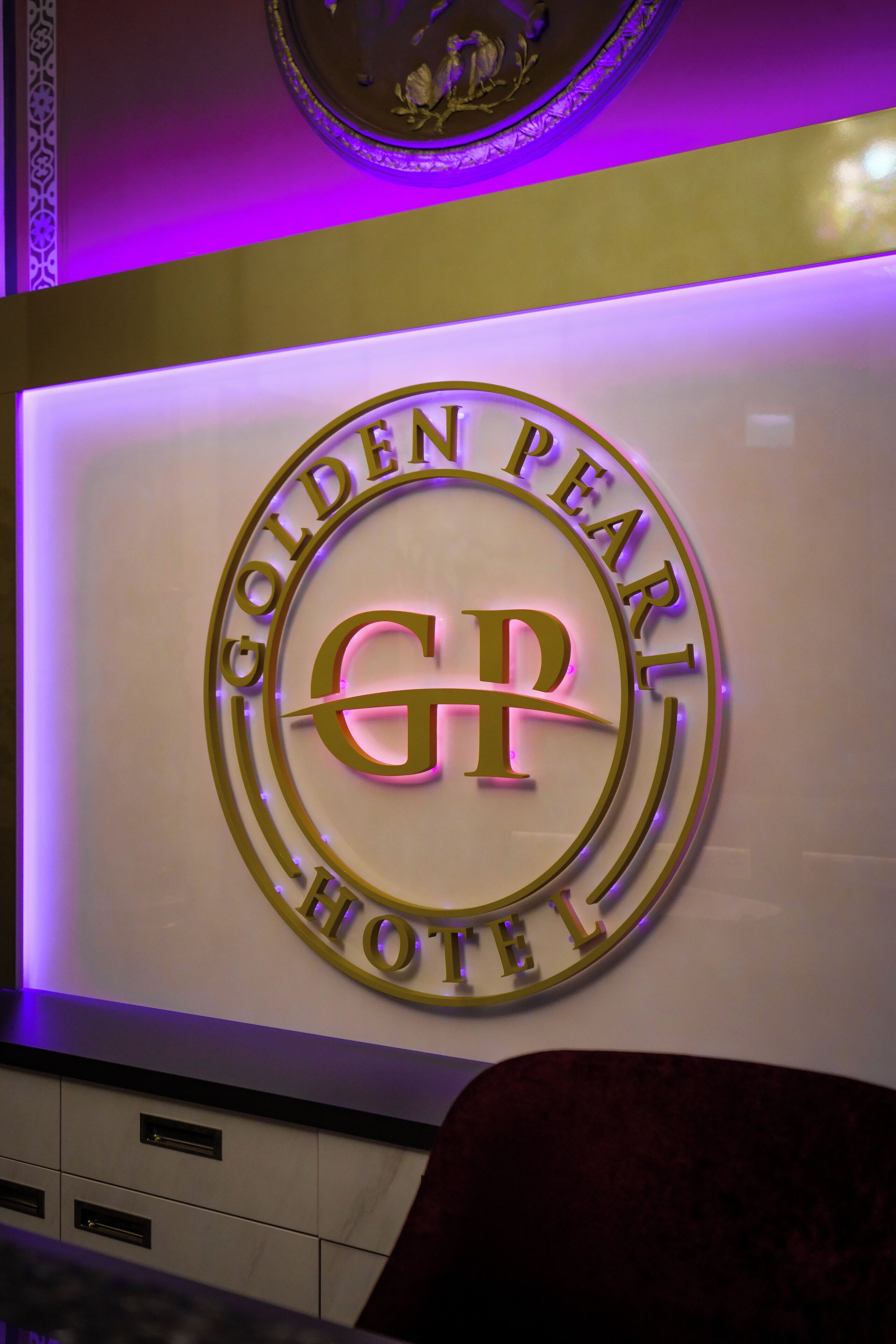 Une enseigne fixée au mur, portant le nom de l’hôtel Golden Pearl et affichant son logo de manière bien visible.