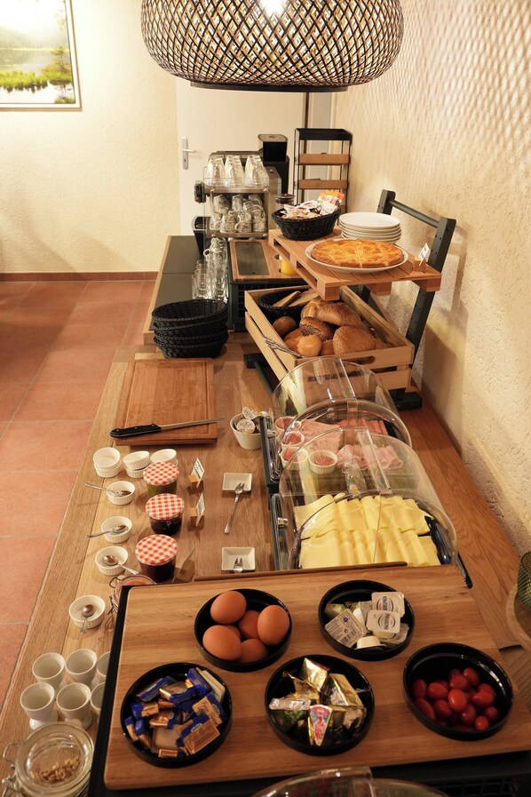 A buffet setup with various food items, utensils, and serving dishes. - Landhaus Meine Auszeit (Bodenmais)