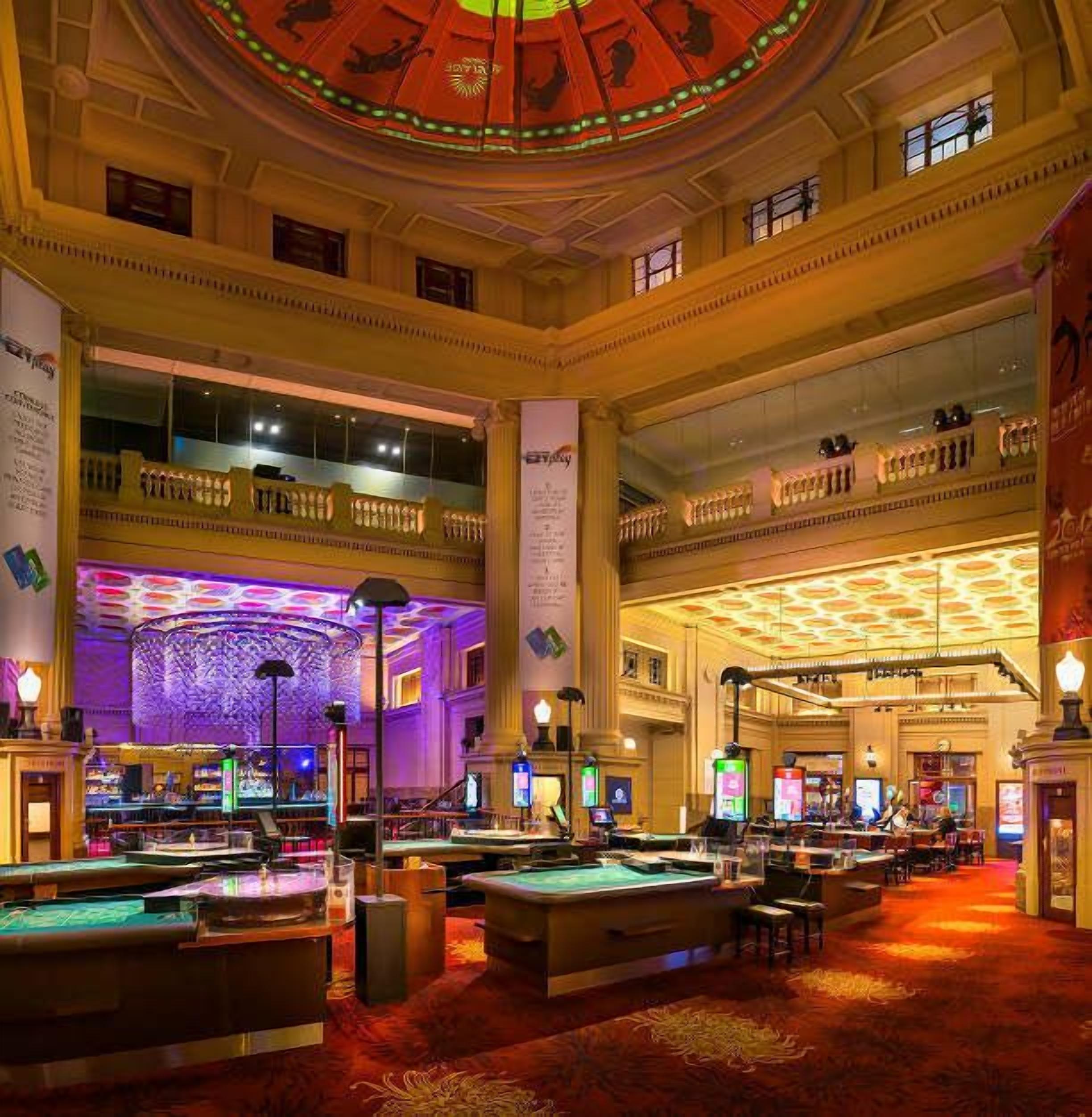 A spacious casino with multiple gaming tables and a grand, ornate ceiling.