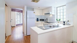 A modern kitchen with white cabinetry, a stainless steel sink, and a microwave.