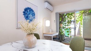 A dining area with a marble table, a vase with flowers, a framed artwork, and a view through a glass door.