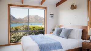 A bedroom with a large window offering a view of a lake and mountains. - Perfectly positioned! (Glamorgan-Spring Bay)