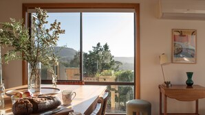 A dining area with a wooden table, a vase with flowers, and a view of the outdoors. - Perfectly positioned! (Glamorgan-Spring Bay)