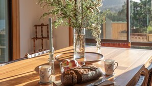 A wooden dining table with a loaf of bread, a glass bowl with apples, and a vase with flowers. - Perfectly positioned! (Glamorgan-Spring Bay)