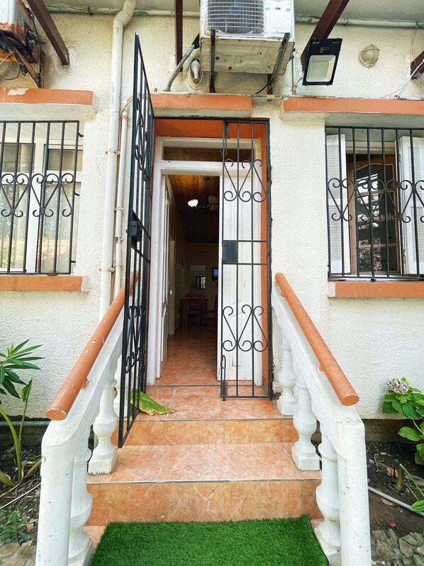 Una entrada de casa con puerta con reja, escaleras y suelo de baldosas.