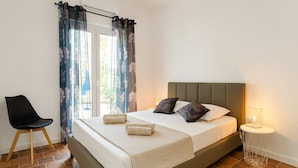A bedroom with a bed, a chair, a bedside table with a lamp, and curtains. - Villa Sole e Mare | 200 m from the beach, bungalow 4 bedrooms, garden 1500 sqm (Biguglia)
