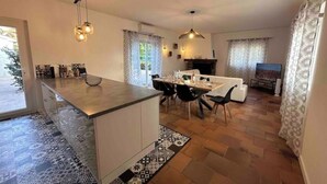 Eine moderne Küche mit einer zentralen Kochinsel, Essbereich mit Stühlen und einem Kamin.