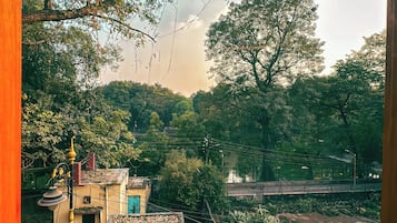 Paisaje rural con árboles, un puente y un edificio con techo inclinado.