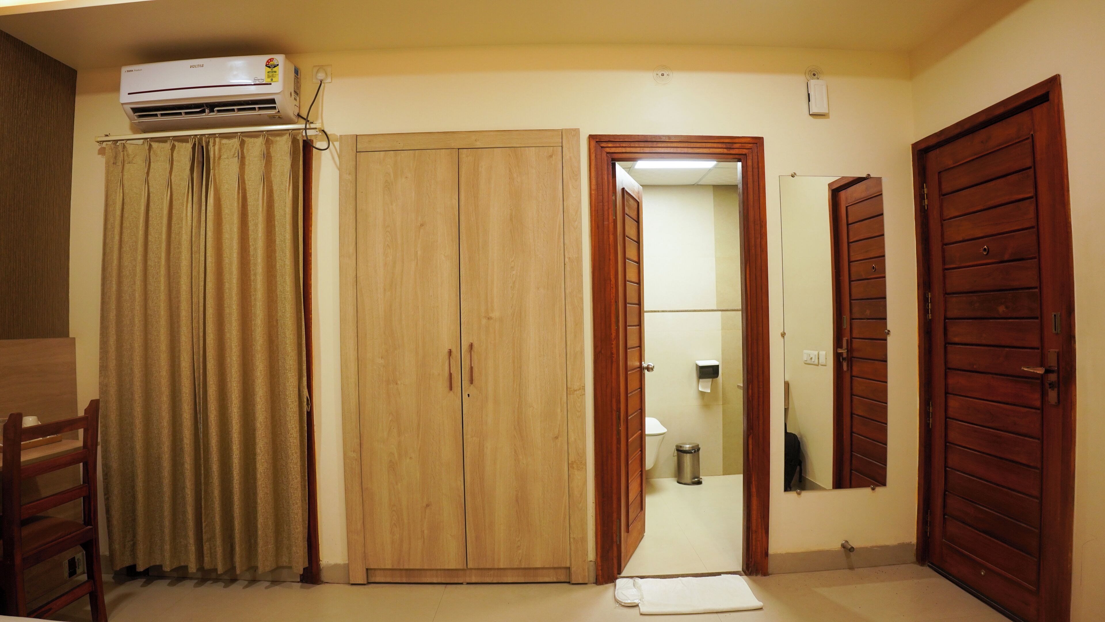 Una habitación con un armario de madera, un espejo y una puerta que da a un baño.