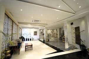 Un hall amplio con una zona de estar central, una escalera y paneles decorativos en las paredes.
