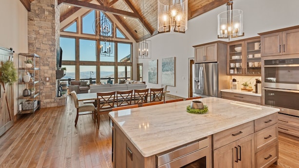 A spacious kitchen with a large island, wooden cabinets, and a stone wall.
