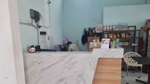 A reception area with a marble counter, a wooden desk, and a shelf with snacks and bottled water. - BI Hotel Kisaran (West Kisaran)