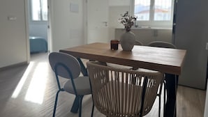 A modern kitchen with a wooden table, two chairs, a vase with dried flowers, and hanging pendant lights. - Casa rural Los Alcornocales (Alcala de los Gazules)