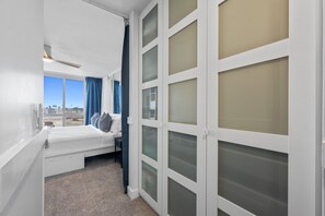Une chambre à coucher avec un lit, une table de chevet, une fenêtre avec des rideaux et une vue sur la ville.