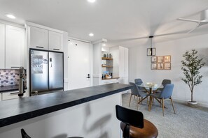 Una cocina moderna con encimera negra, armarios blancos y refrigerador empotrado.