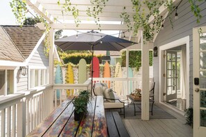 Une terrasse couverte avec une table en bois, des chaises et une plante en pot.