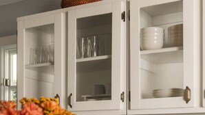 Een keuken met witte kastjes, een grijze spatwand en een houten aanrecht.
