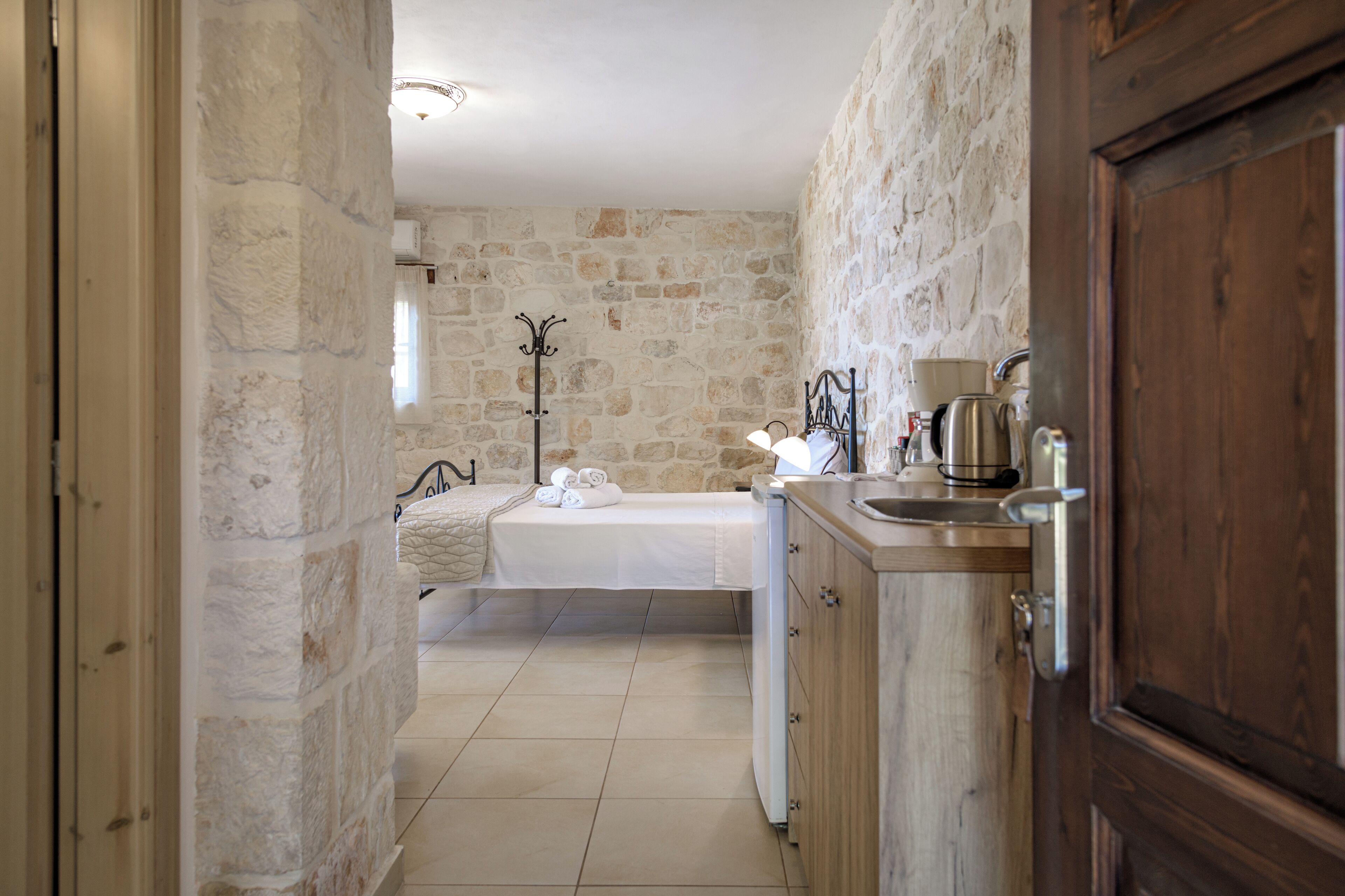 A bedroom with a stone wall, a bed, a bedside table, and a nightstand.