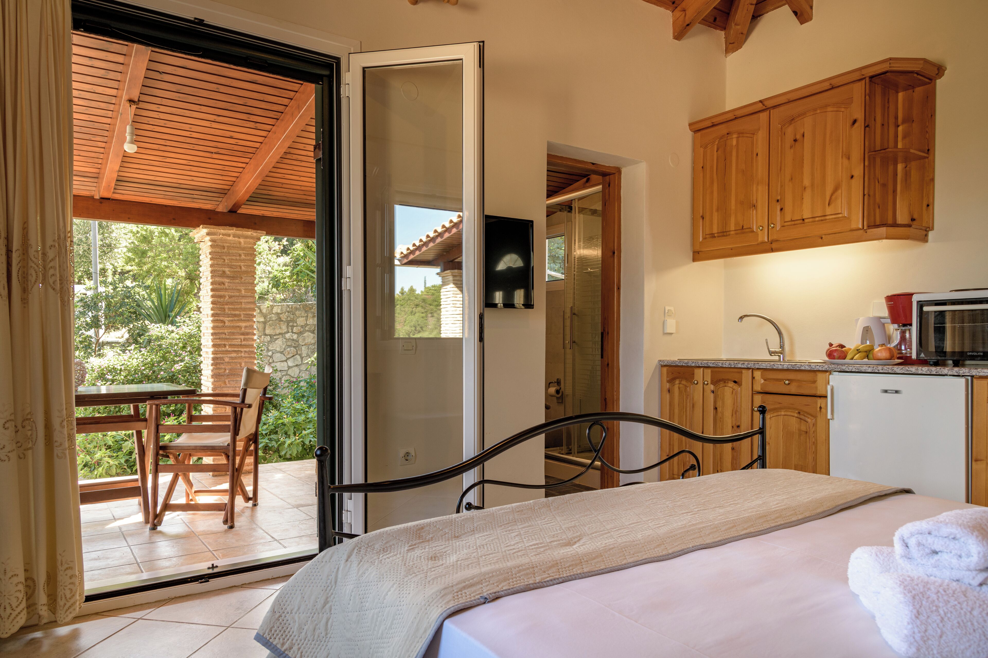 A bedroom with a bed, a bathroom with a shower, and a kitchen with wooden cabinets.