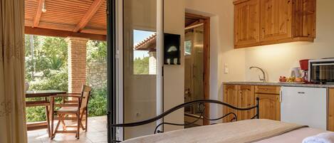 A bedroom with a bed, a bathroom with a shower, and a kitchen with wooden cabinets.
