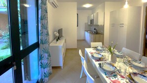 Una cocina moderna con armarios blancos, una mesa de comedor preparada para seis personas y vistas al exterior a través de un ventanal.