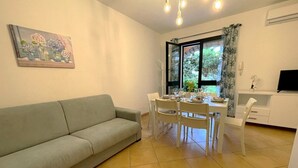 Una sala de estar con sofá, mesa de comedor, sillas y televisor.