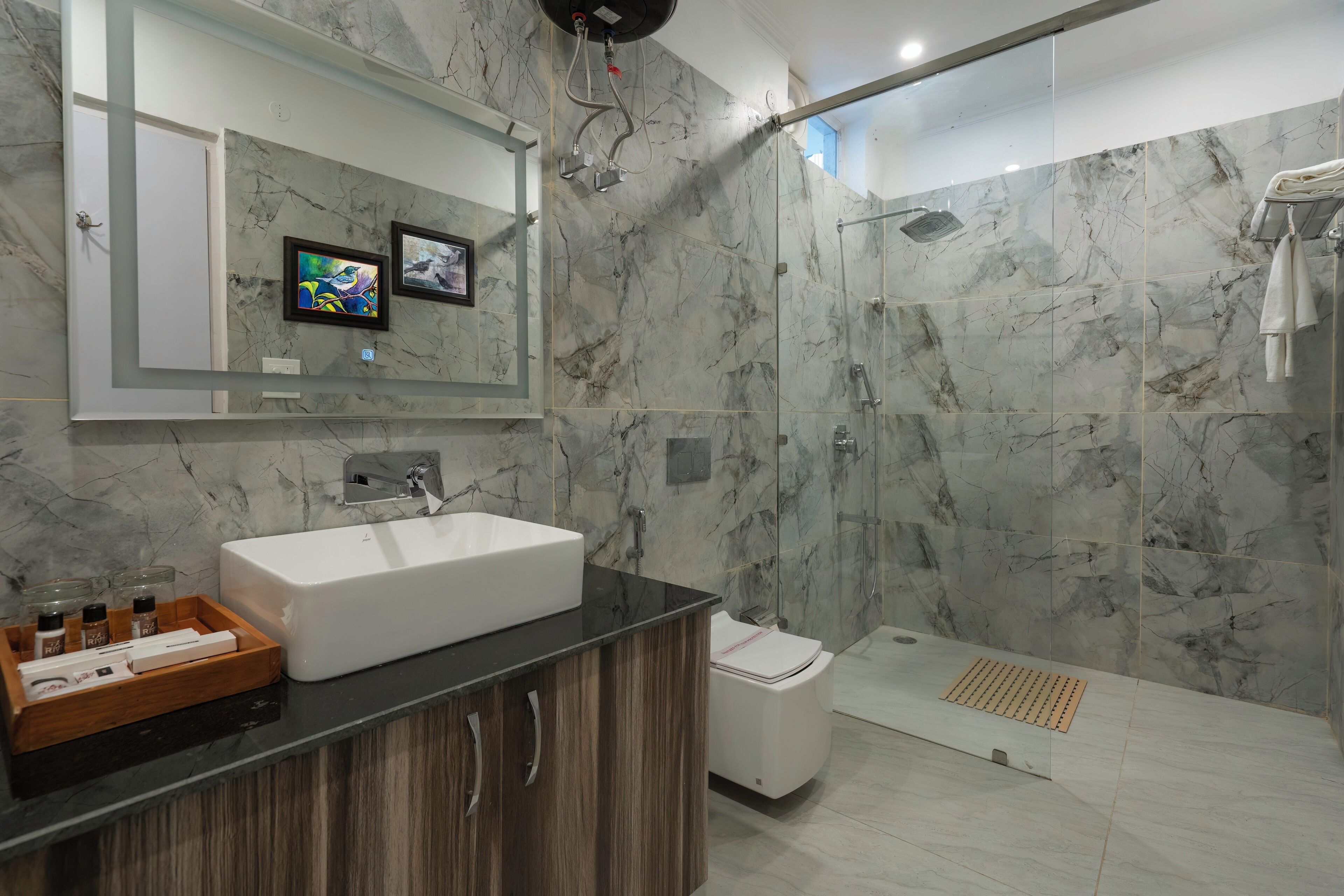 Un baño moderno con un lavabo blanco grande, una ducha con puerta de cristal y paredes de mármol.