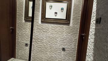 Un baño con pared de piedra, un espejo enmarco y piso de baldosas.