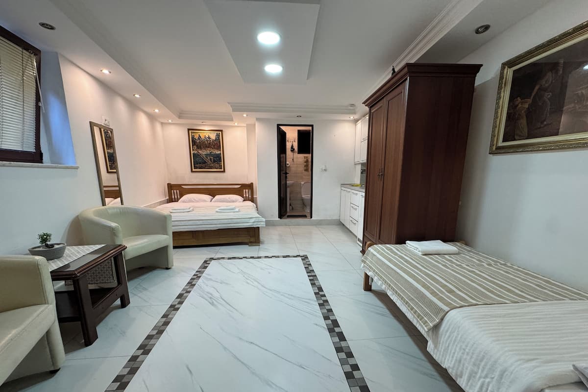 A hotel room with a bed, a sofa, a desk, and a wardrobe.