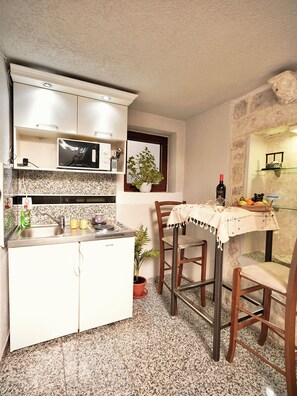 A compact kitchen with a microwave, sink, and potted plants.
