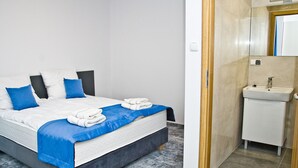 A hotel room with a bed, a bathroom with a sink, and a mirror. - ParkApartamenty (Chrzanow)