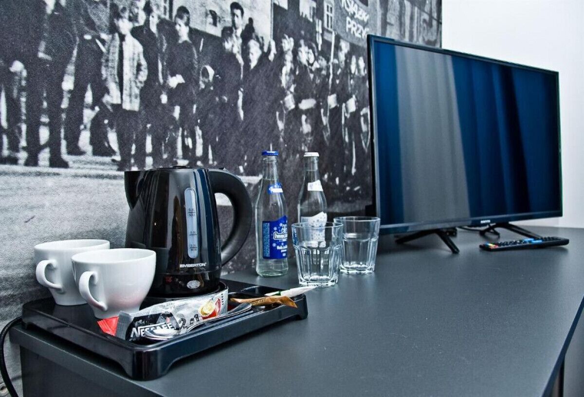 A desk with a coffee maker, cups, a bottle of water, and glasses.