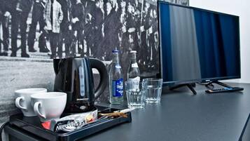 Een bureau met een koffiezetapparaat, bekertjes, een waterfles en glazen.