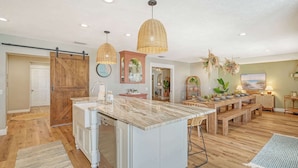 A modern kitchen with a marble countertop, wooden cabinets, and a sliding barn door.
