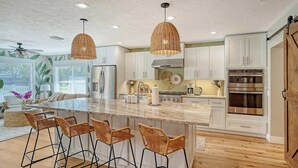 A modern kitchen with white cabinets, stainless steel appliances, and a central island with bar stools.