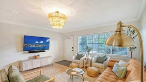 A living room with a television, sofa, chairs, a coffee table, and a floor lamp.