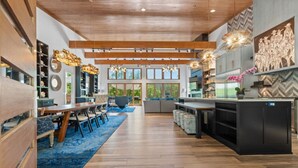 A spacious kitchen with modern appliances, a dining area with a blue rug, and a large window providing natural light. - Luxurious Retreat | Private Creek View | Hot Tub (Hot Springs)