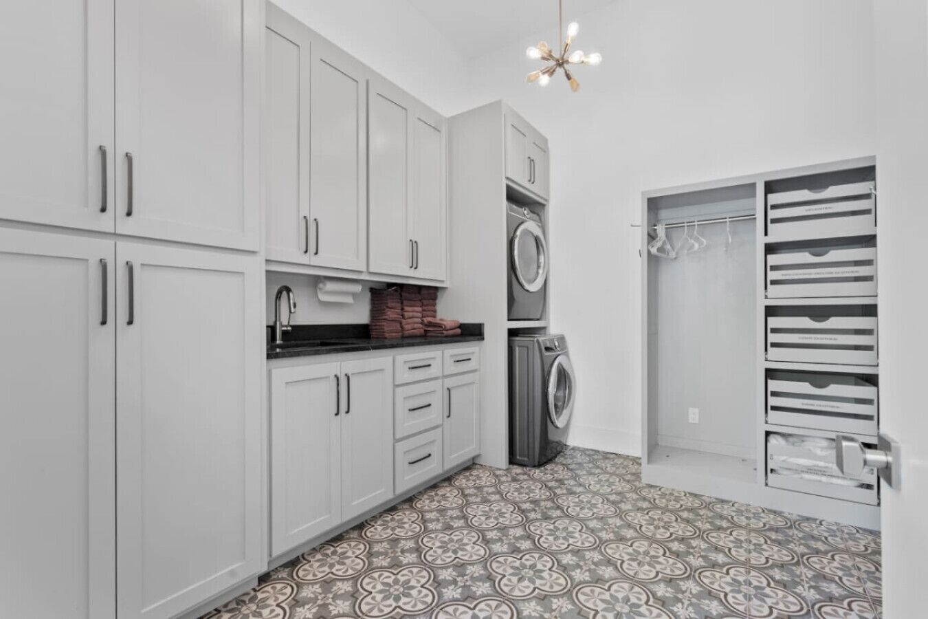 Una cucina compatta con mobili bianchi, una lavatrice e uno stendibiancheria.