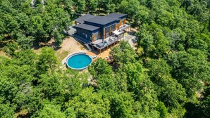 A modern house with a swimming pool surrounded by dense forest. - Luxurious Retreat | Private Creek View | Hot Tub (Hot Springs)