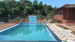 Une piscine rectangulaire bordée de carreaux et agrémentée d’un mur en pierre servant d’élément décoratif.