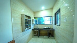 Une petite cuisine étroite, carrelée, avec des murs en bois, une fenêtre et une étagère intégrée.