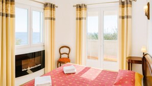 Ein Hotelzimmer mit Bett, Stuhl, Kamin und Meerblick.
