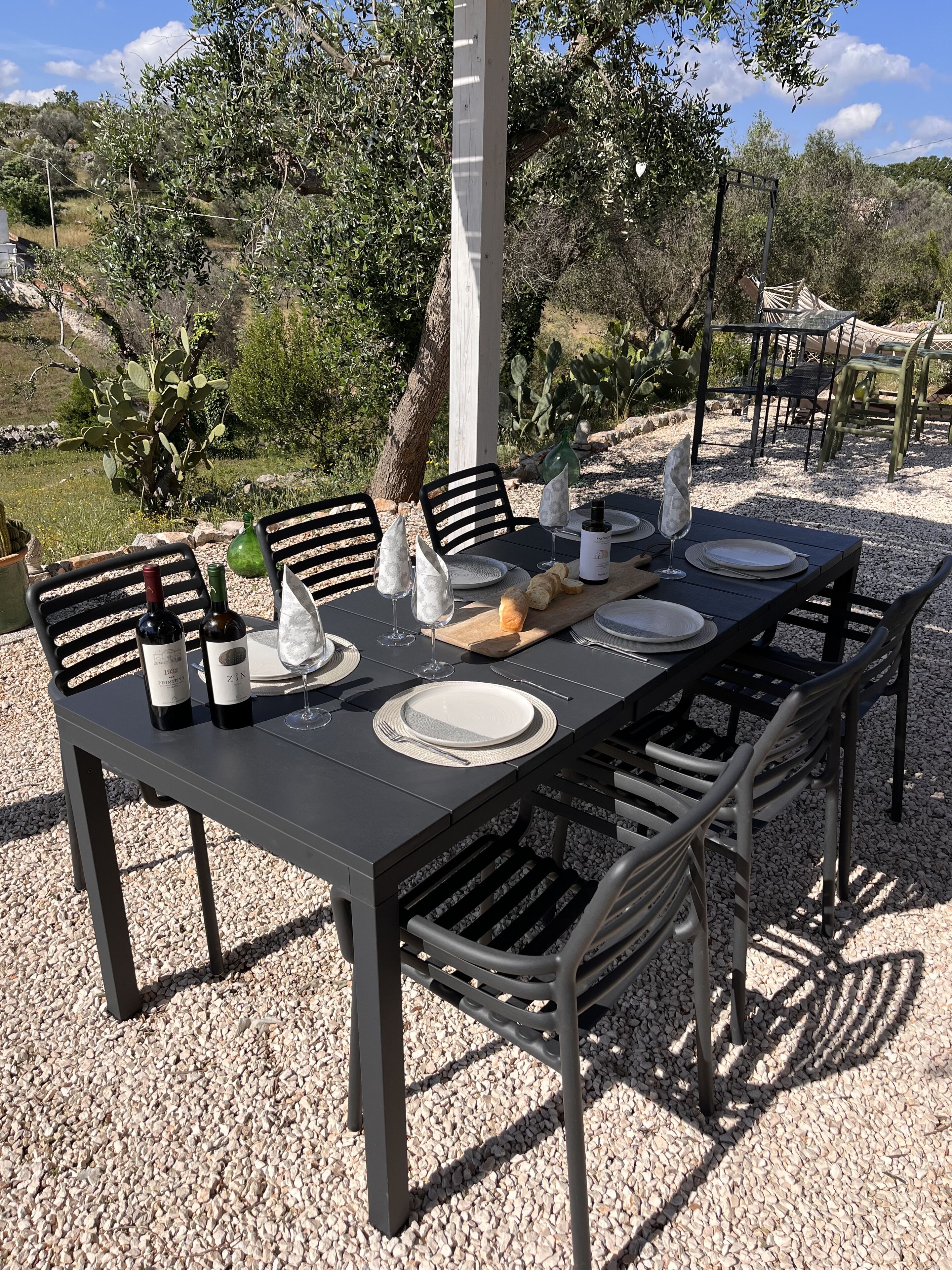 Ein Essbereich im Freien mit Tisch für vier Personen, umgeben von Stühlen, und einer Pergola darüber.