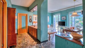 A spacious kitchen with a dining area, a wooden cabinet, and a television. - Simply Romantic Alassio Sea View (Alassio)