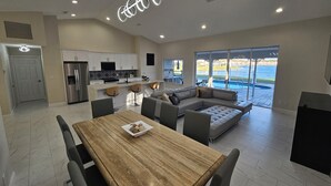 A modern kitchen with white cabinets, a stainless steel refrigerator, and a black and white backsplash. - Brand New!! Spacious Elegant Home with Heated Pool, BBQ and Amazing Lake Views (Naples)
