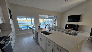 A modern kitchen with a large island, built-in appliances, and a view of a pool. - Brand New!! Spacious Elegant Home with Heated Pool, BBQ and Amazing Lake Views (Naples)