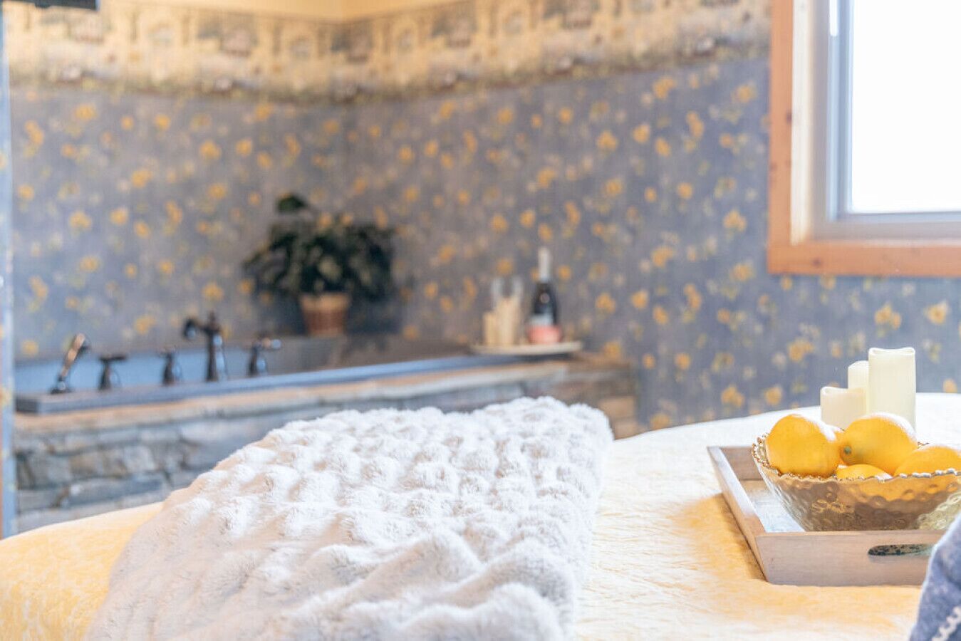 A room with a stone wall, a bathtub, and a window.
