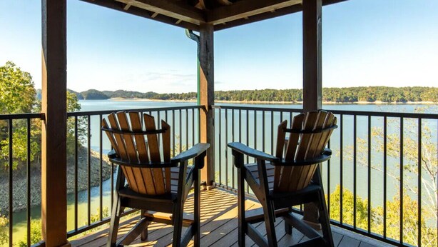 Une terrasse couverte avec deux fauteuils Adirondack donnant sur un lac.