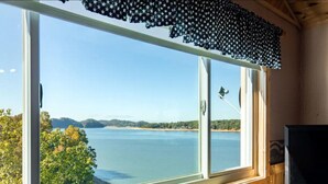 Une pièce dotée d’une grande fenêtre donnant sur une étendue d’eau, d’un intérieur en bois et d’un téléviseur posé sur un meuble en bois.