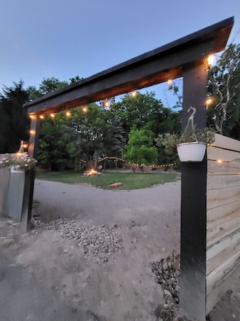 A wooden pergola with string lights, a potted plant, and a small statue.. Comfortable 1 bedroom apt with hot tub access.